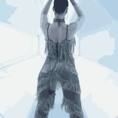 a woman in a fringed dress is dancing in a white room .