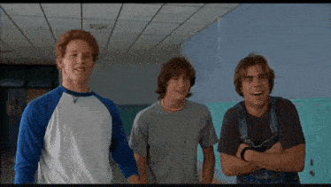 three young men standing next to each other in a hallway with lockers in the background