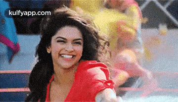 a woman in a red shirt is smiling in front of a crowd of people .