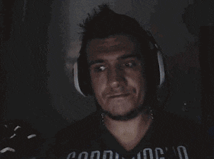 a man wearing headphones is dancing in front of a computer screen in a dark room .