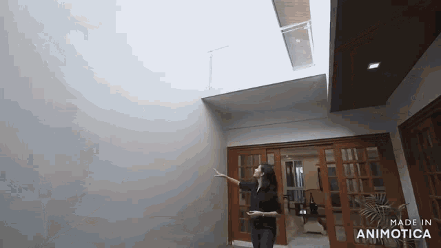 a woman stands in a room with the words made in animatica on the bottom right
