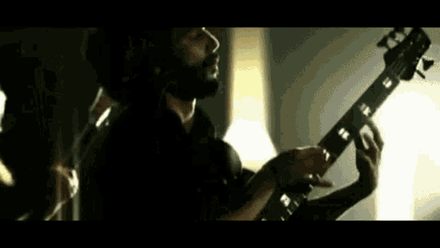 a man with a beard is playing a guitar in a room .