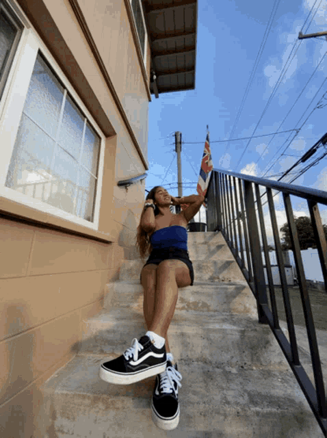 a woman is sitting on a set of stairs wearing black vans shoes