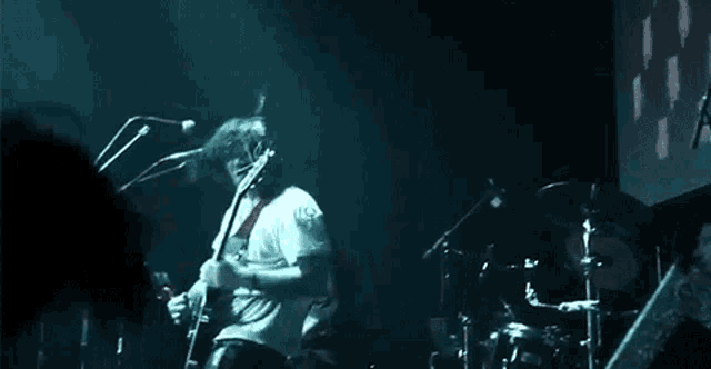 a man playing a guitar in front of a drum set