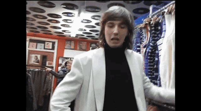 a man in a white jacket and black turtleneck is in a store