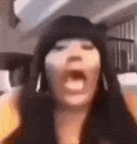 a woman wearing a hat is making a funny face with her mouth open .