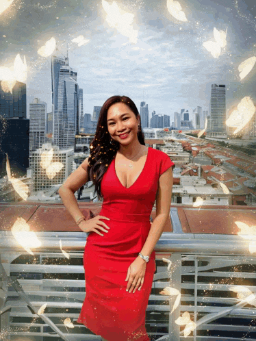 a woman in a red dress stands on a balcony with a city in the background