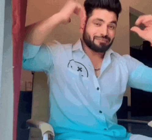a man with a beard is wearing a blue shirt with a smiley face on it