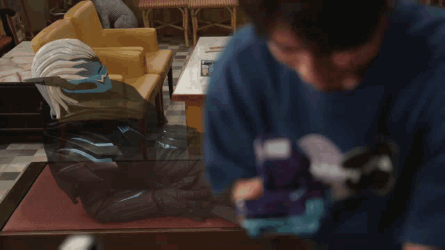 a man wearing a blue shirt with a circle on it is standing in a room