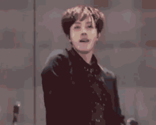 a man in a black suit is dancing on a stage in front of a red light .