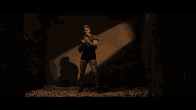 a man is standing in a dark room with a shadow on the wall