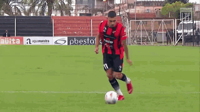 a man in a red shirt is kicking a soccer ball on a soccer field