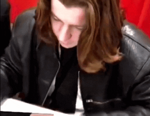 a young man with long hair wearing a black leather jacket