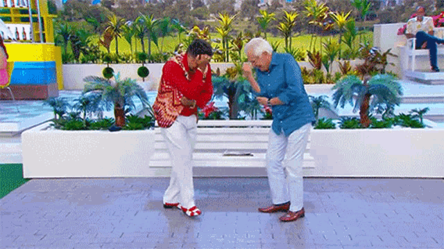 two men are dancing in front of a white bench in a garden .