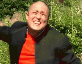 a bald man in a red shirt and black jacket is smiling