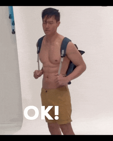 a shirtless man with a backpack is standing in front of an ok sign