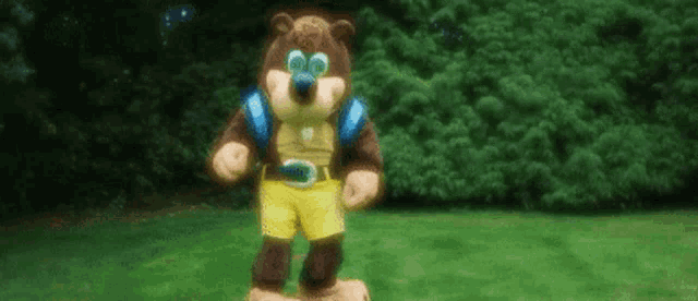 a teddy bear is standing on top of a lush green lawn .