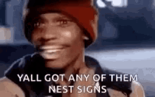 a man wearing a red beanie is smiling and says `` yall got any of them nest signs '' .