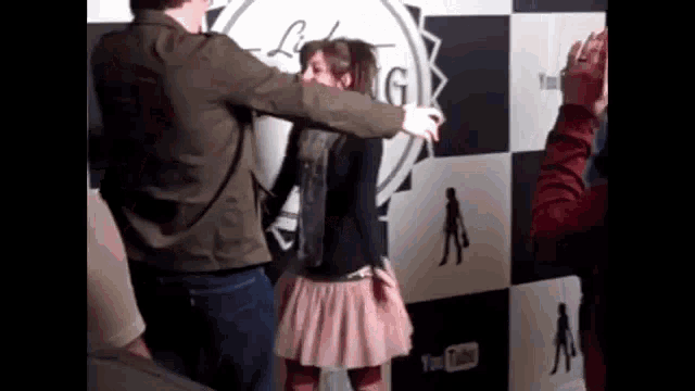 a woman in a pink skirt is being hugged by a man