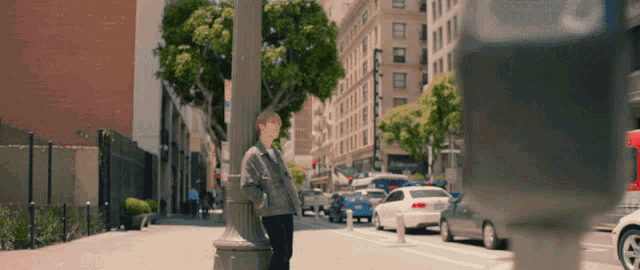 a man leaning against a pole on a city street with a parking meter in the foreground