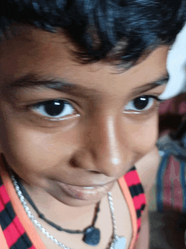 a close up of a child 's face with a necklace