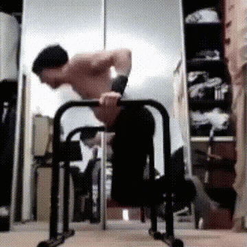 a man is doing push ups on a bar in front of a mirror in a room .