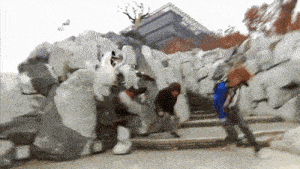 a group of people are standing in front of a large rock