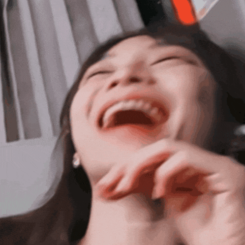 a close up of a woman laughing with her eyes closed