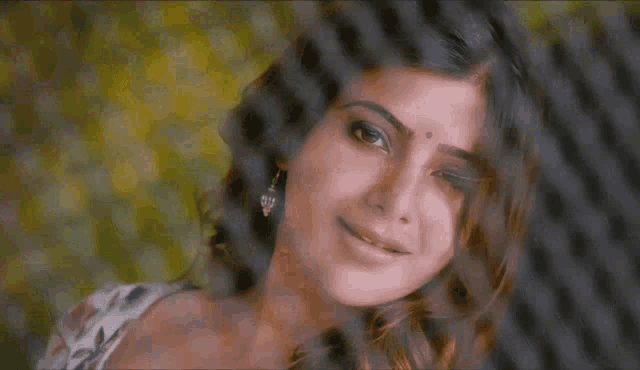 a close up of a woman behind a chain link fence smiling