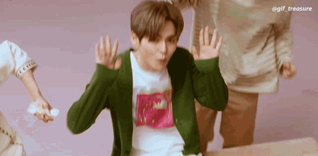 a man in a green jacket is making a funny face with his hands