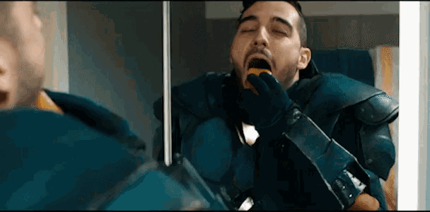 a man in a blue armor looks at himself in the mirror