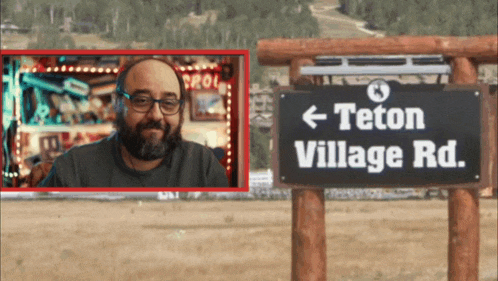 a man stands in front of a sign for teton village road