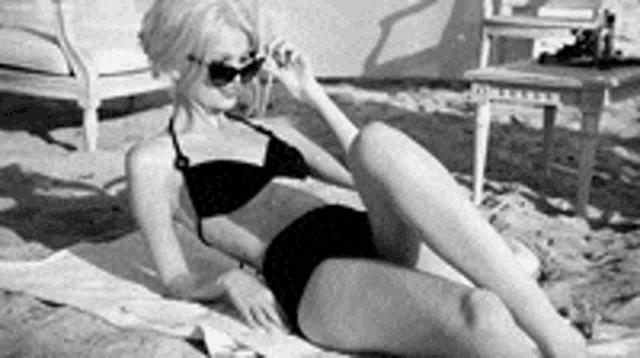 a woman in a bikini is laying on a beach .