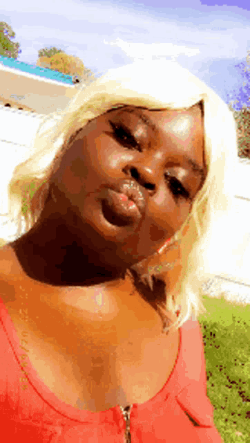 a woman in a red top is blowing a kiss at the camera