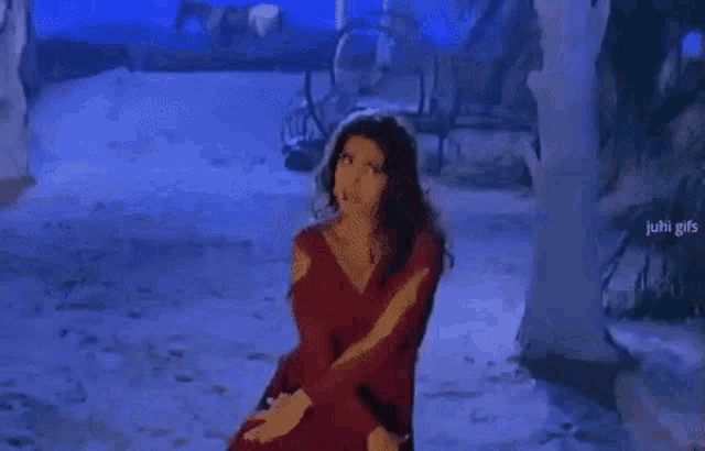 a woman in a red dress is dancing in a snowy forest .