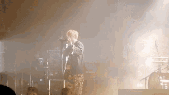 a man singing into a microphone with a crowd behind him