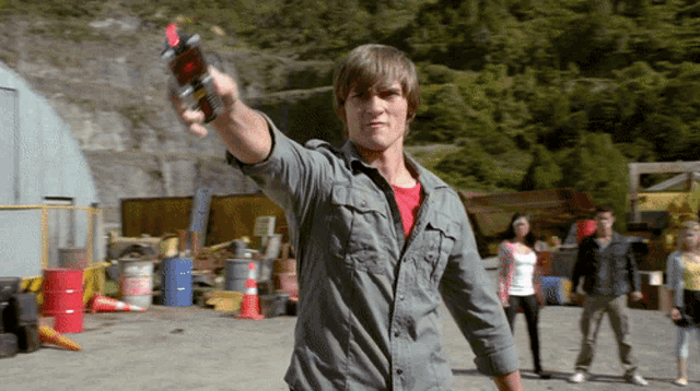 a man in a grey shirt holds up a red object