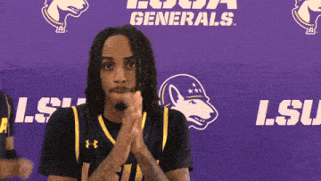 a man clapping in front of a purple banner that says lsu