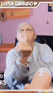 an elderly woman with glasses is giving the middle finger .