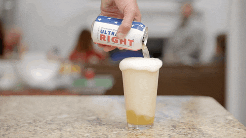 a person pouring a can of ultra right into a glass
