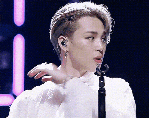 a man in a white shirt is singing into a microphone while wearing earphones .
