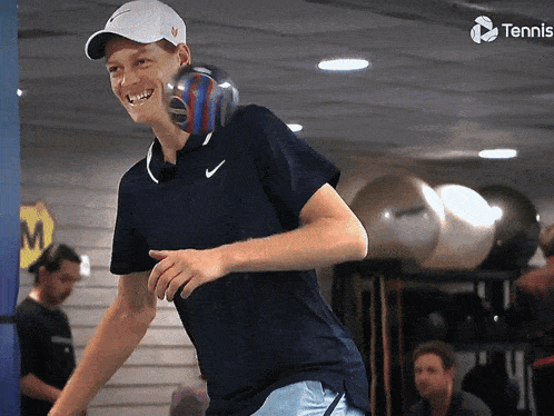 a man wearing a nike shirt is smiling and holding a tennis ball
