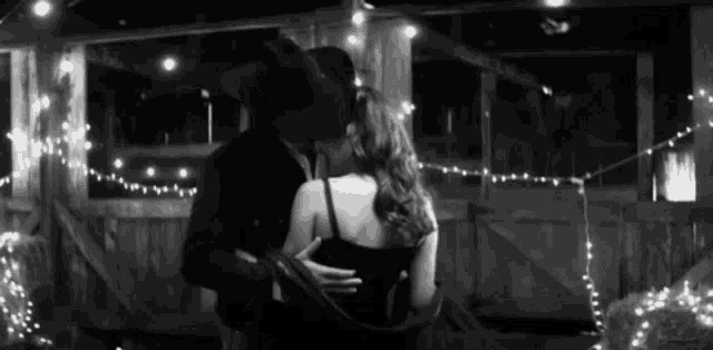 a man in a cowboy hat is kissing a woman in a black dress