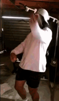 a man in a pink shirt is dancing in a garage .