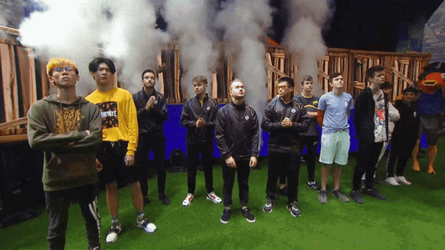 a group of young men are standing in front of smoke coming out of a wooden fence