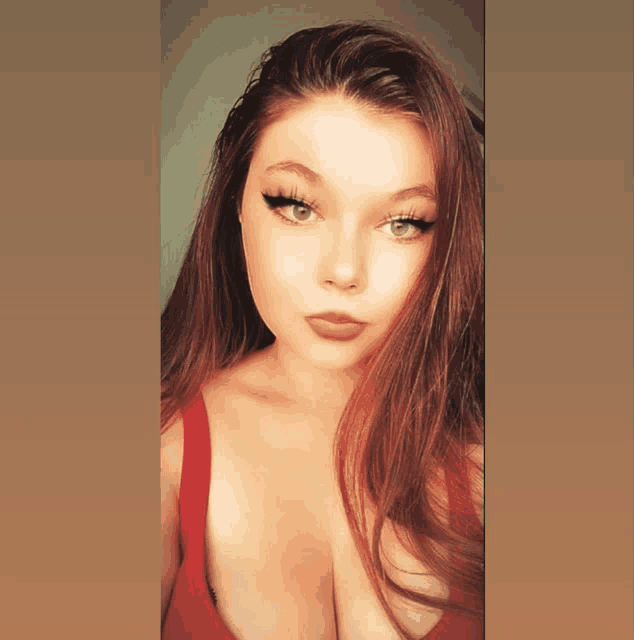 a woman with long red hair and green eyes is wearing a red top