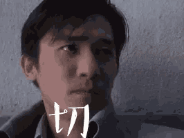 a close up of a man 's face with chinese writing on the wall .