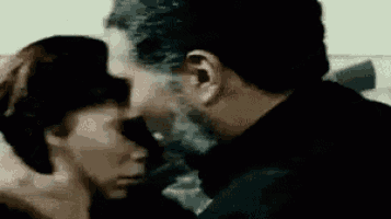 a man and a woman are kissing each other in a room .