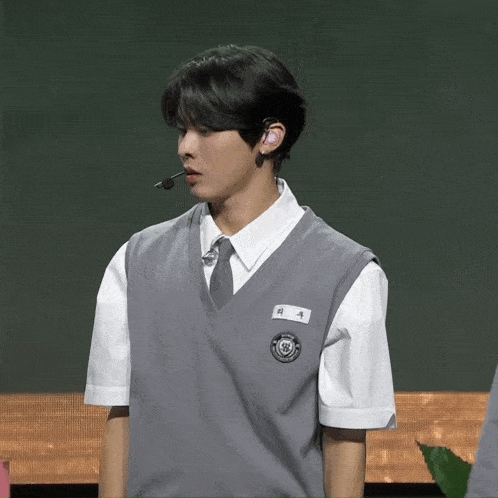 a man wearing a gray vest and a white shirt has a name tag that says ' hyun '