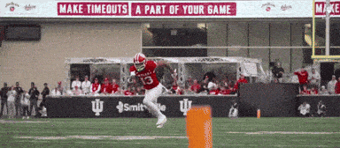 a football player with the number 13 on his jersey jumps over a fence